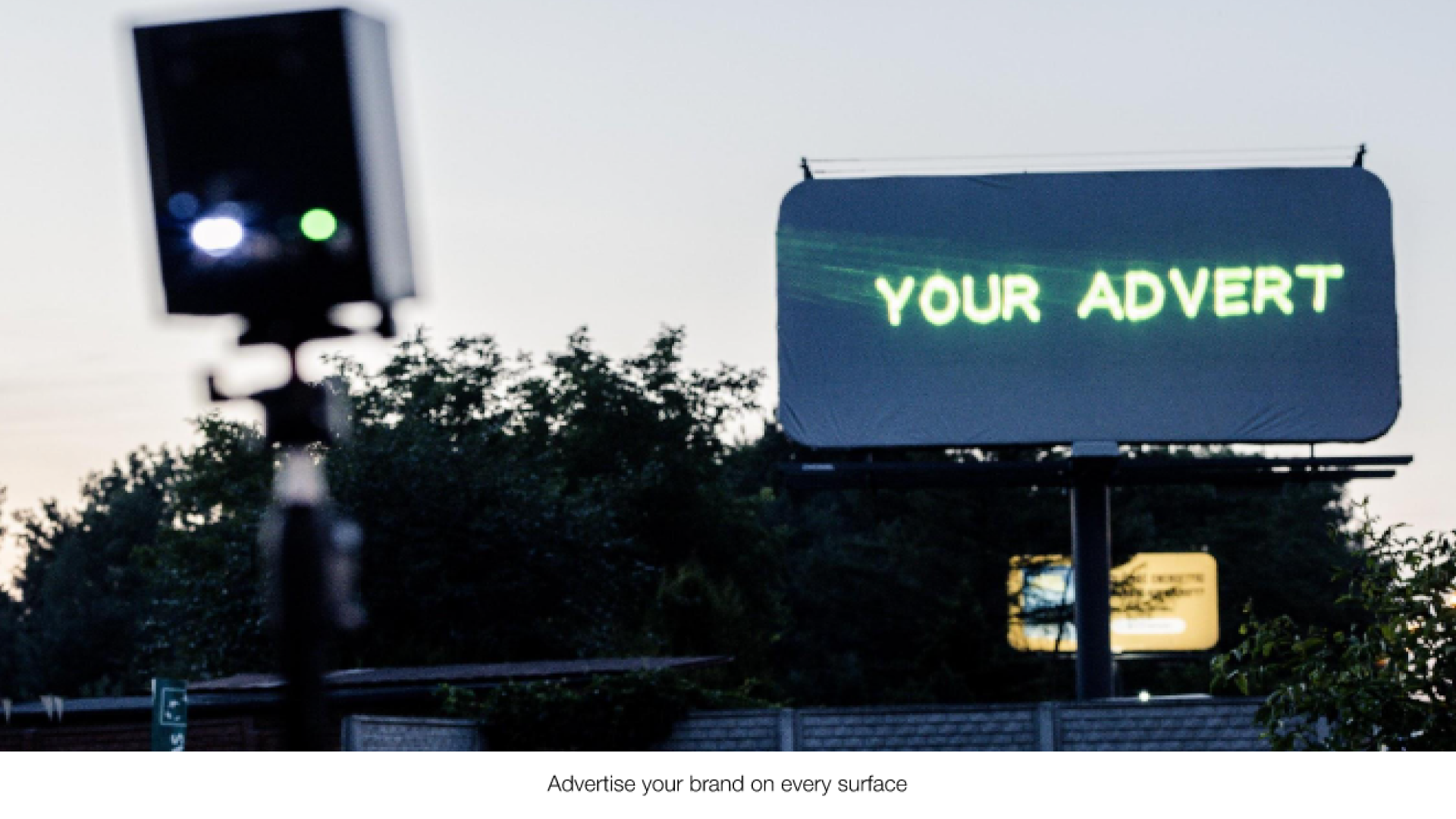Advert_img A blank outdoor billboard with the text "your advert" projected onto it from a Lasercube laser projector, showcasing how it can be used for outdoor advertising