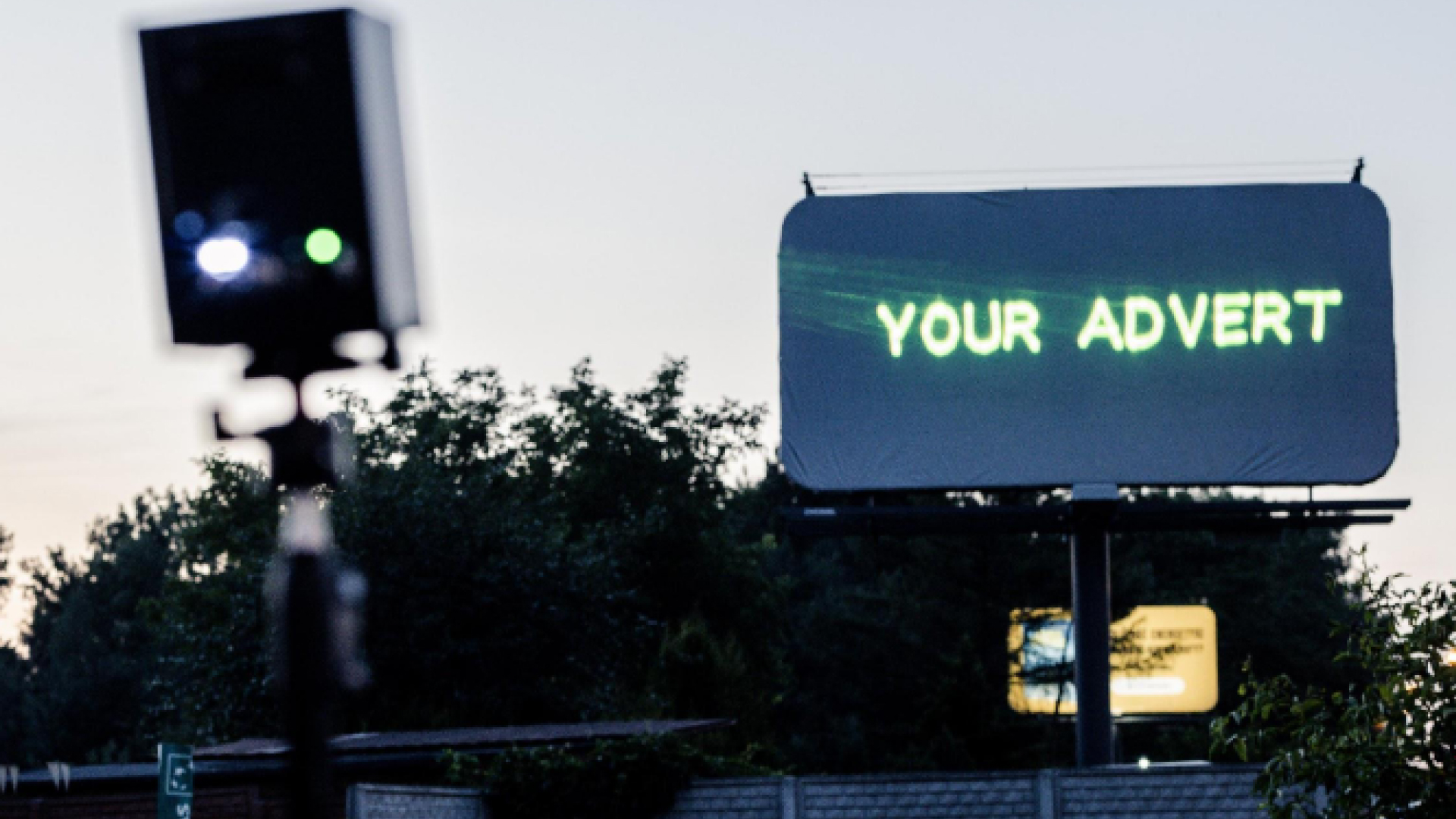 blog_Banner_img A blank outdoor billboard with the text "your advert" projected onto it from a Lasercube laser projector, showcasing how it can be used for outdoor advertising