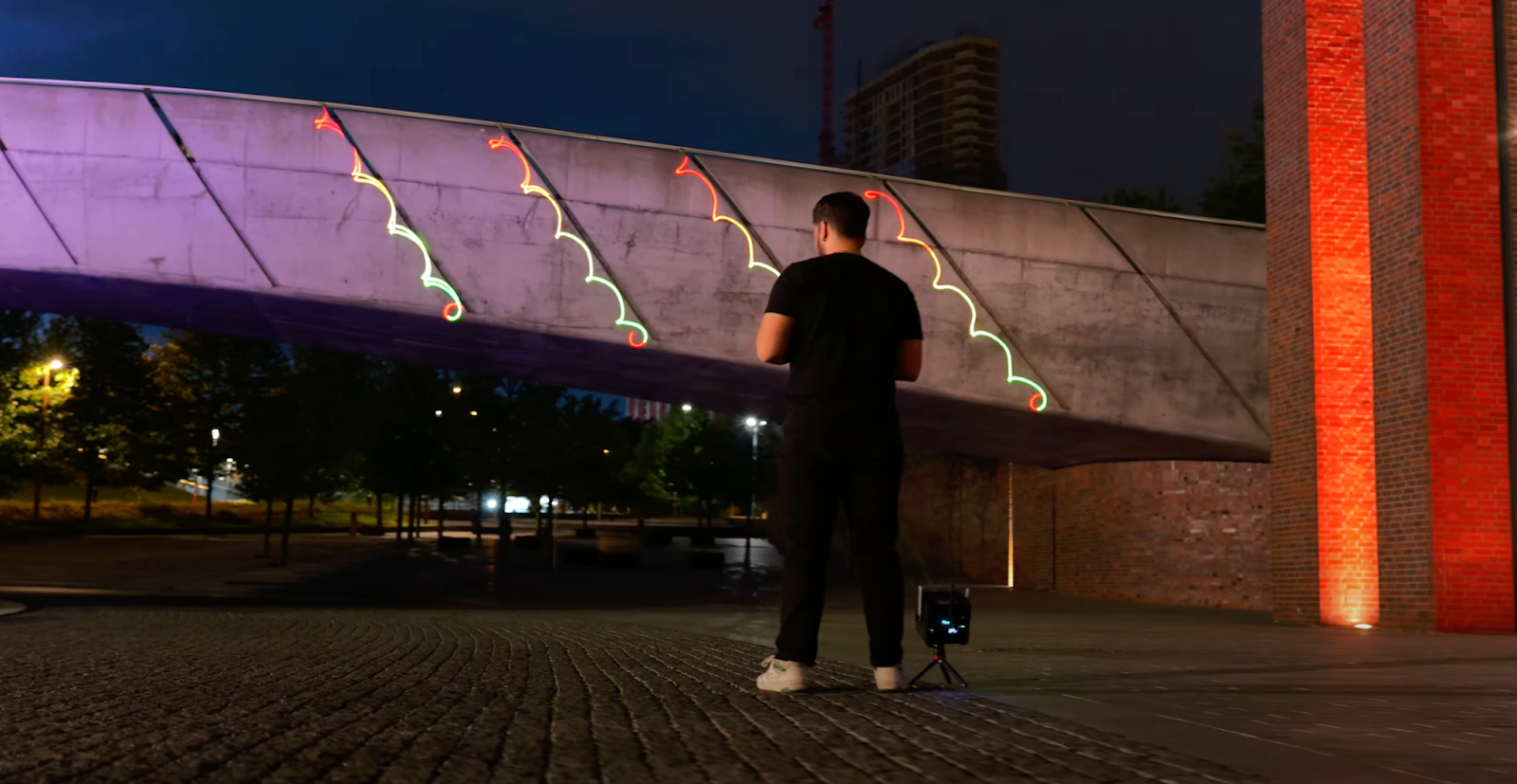 unnamed (3) Person using the LaserCube laser show projector to show laser on a bridge