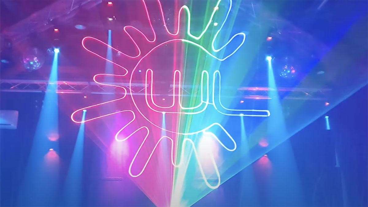 7 Laser projection through smoke on a stage showing green and red laser lights, with the Wicked Laser logo.