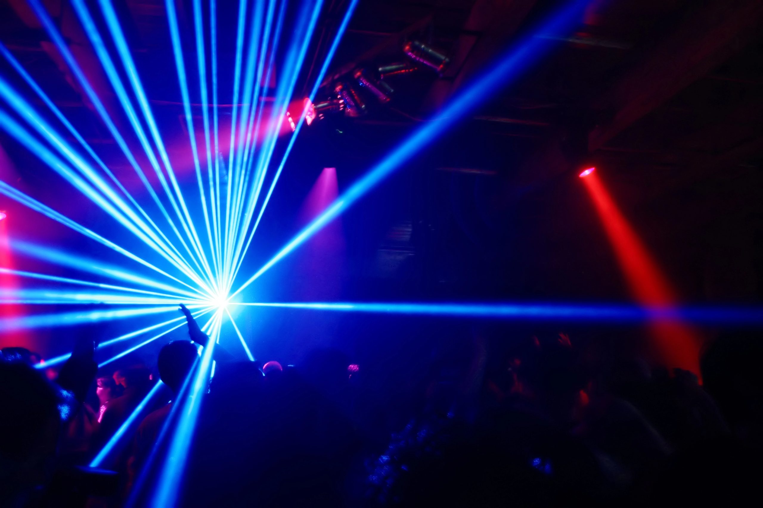 blue laser light projected from a laser projector at a disco party blue laser light projected from a laser projector at a disco party